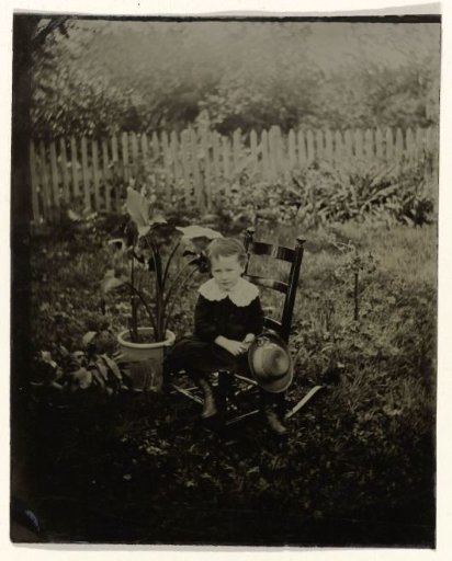 Portrait of a boy sitting on a chair in a garden