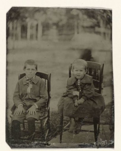 Portrait of two boys sitting on a chair in a garden or park
