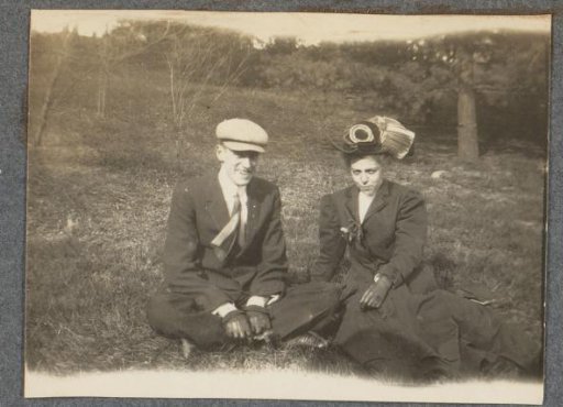 Young man and woman on a grassy field at the edge of a forest