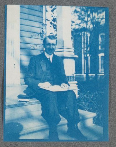 Student with a book on a porch, possibly on the campus of Denison University in Ohio