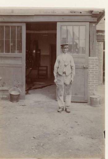Portrait of an unknown craftsman or worker in front of a workshop