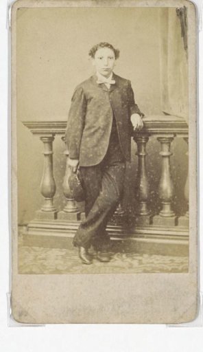 Portrait of a standing young man with a cap in his hand