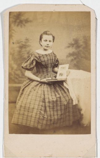 Portrait of a young girl in a checkered dress holding a photo album