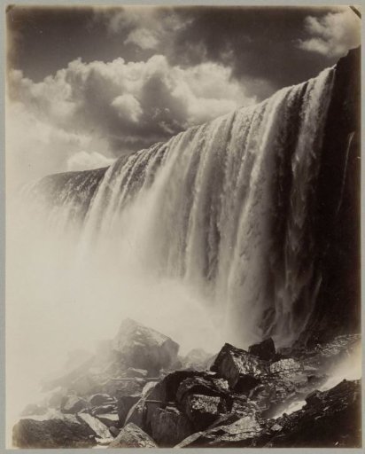 View of the falling water of Niagara Falls with rocks in the foreground