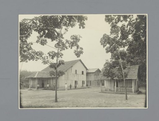 Local Workers and a European in Front of Buildings on the Paul Sandel Plantation, Sumatra