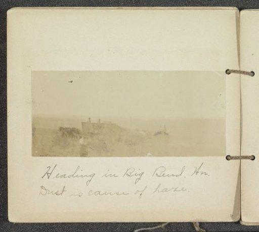 Horse-drawn reaping machine in a cloud of dust