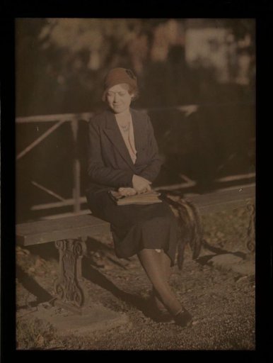 Woman seated on a bench on a bridge