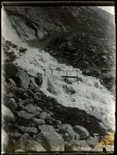 Mountain landscape with a waterfall and a wooden bridge