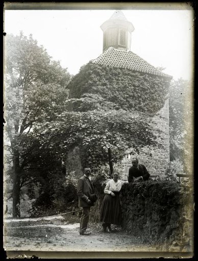 Woman and two men at a tower in a garden