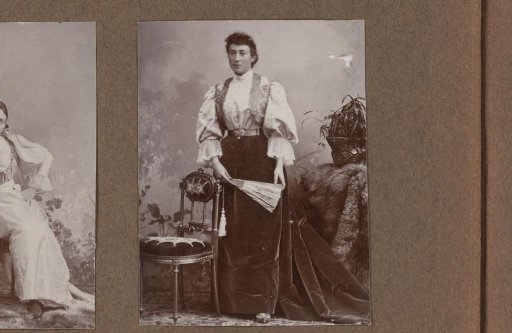 Studio portrait of a standing woman with a fan