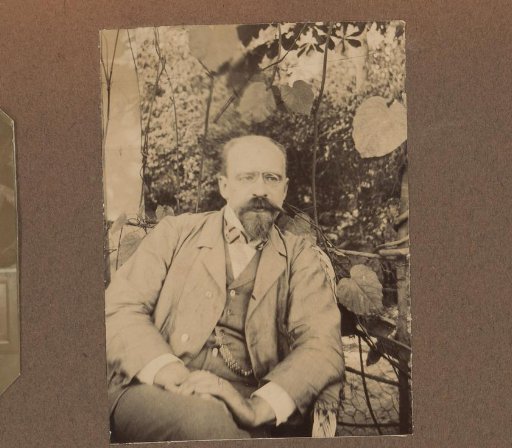 Seated man with spectacles and beard in a garden
