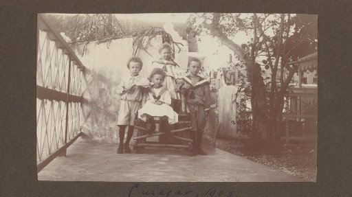 Portrait of four children outdoors on a wooden bench in Curaçao, presumably the children of Jan Olphert de Jong van Beek en Donk