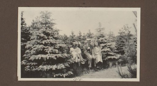 Alphons Diepenbrock among his daughters Joanna and Thea on a bench among the conifers, presumably in the garden of country house De Bijlakker