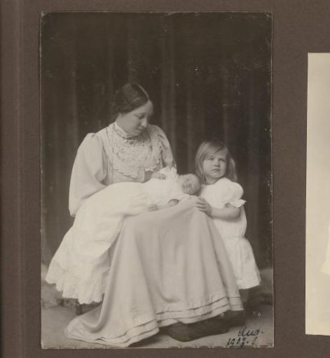Portrait of Elsa Diepenbrock with Thea on her lap in a christening gown and Joanna standing beside her
