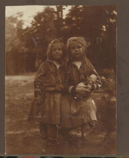 Portrait of Thea and Joanna Diepenbrock outdoors in sailor dresses with a doll