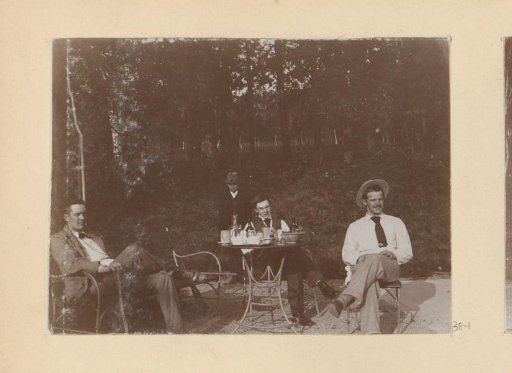 Company seated at a table next to a tennis court