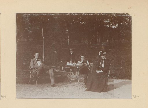 Company Seated at a Table Next to a Tennis Court