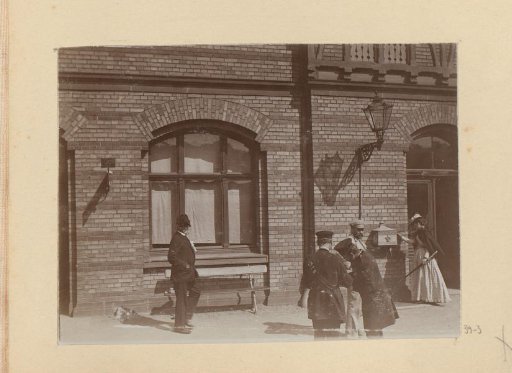 Persons, presumably train or boat conductors, in front of a building