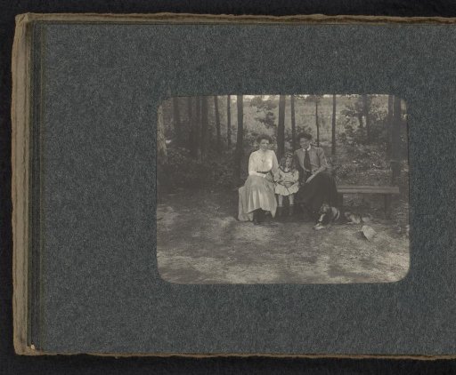 Three members of the Van den Berg family with a dog, sitting on a bench on the heath in Huis ter Heide