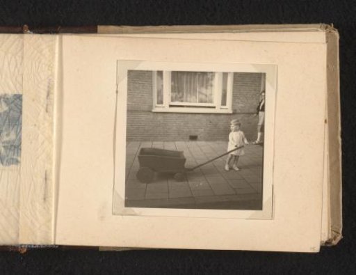 Norbert Peter van den Berg as a toddler with a pushcart on the street, in front of a window frame