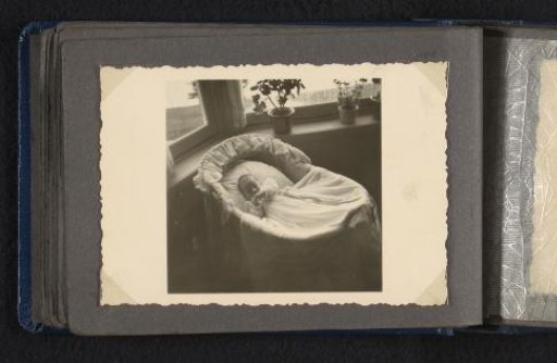 Norbert Peter van den Berg as a newborn baby in a christening gown in a cradle