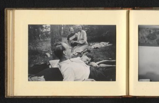 Three women and a man with twigs in his hair, sitting on the ground in a forest