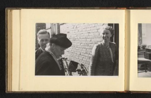 Two women and a man by a stone wall with a bicycle