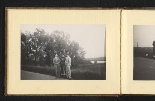 Woman with two men on either side, on a paved road in a natural landscape