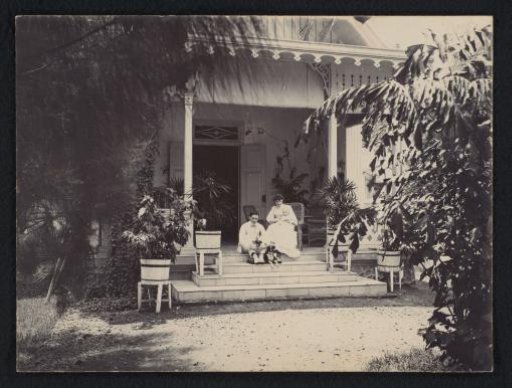 Married couple with baby and child and puppies on the veranda of a large house, Indonesia possibly Surabaya