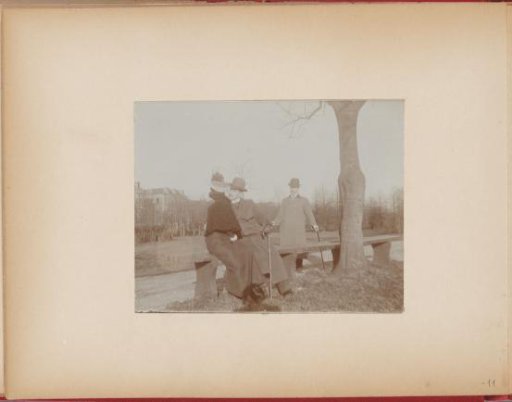 Young couple, the woman with a feathered hat, being kissed on a bench in a park by the man who was spying on her, the other man approaches, photo story 3