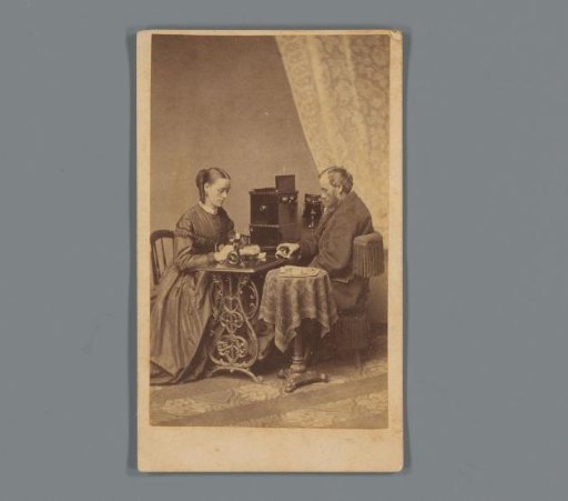 Advertisement for a Willcox & Gibbs sewing machine with portrait of a man and woman at a table