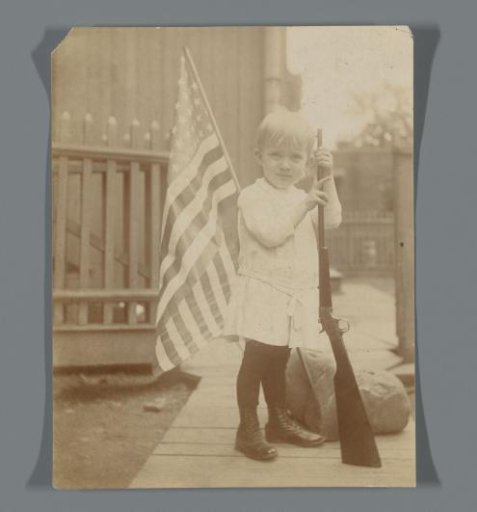 Boy with a rifle and an American flag