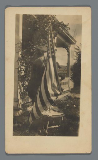 Woman (?) in military uniform before an American flag