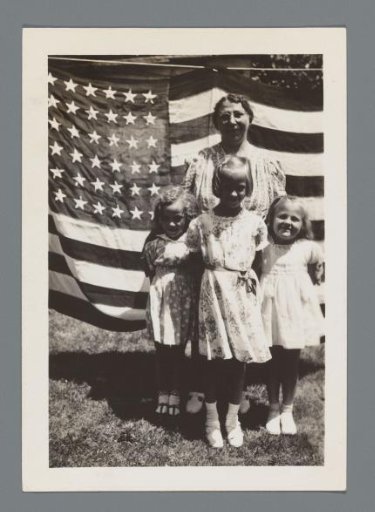 Woman and three daughters standing before an American flag