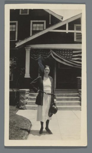 Woman standing before a house with an American flag