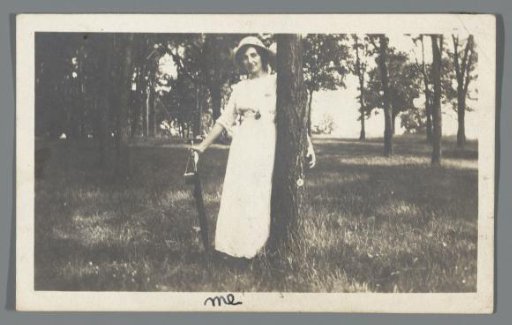 Portrait of a young woman with umbrella and bag, leaning against the tree