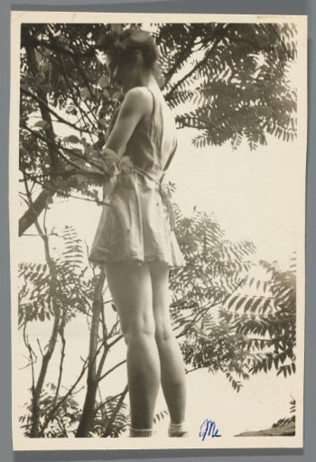 Portrait of a young woman in a short dress among foliage