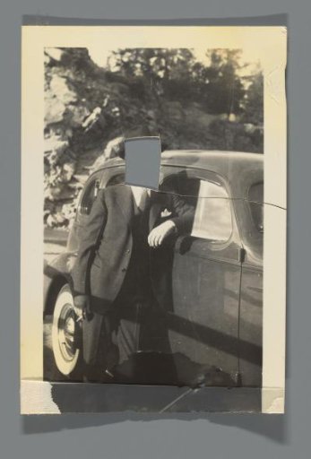 Portrait of a man with a cut-out face leaning on a car door with a cigarette in his hand