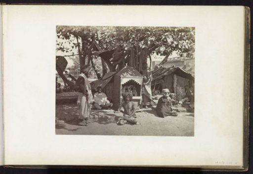 Ascetics by a street in East India with a small shrine of Jagannath behind them