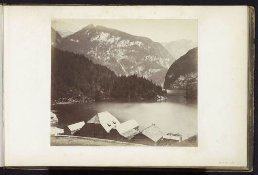 View of a mountain lake with buildings on the shore, possibly in the Alps