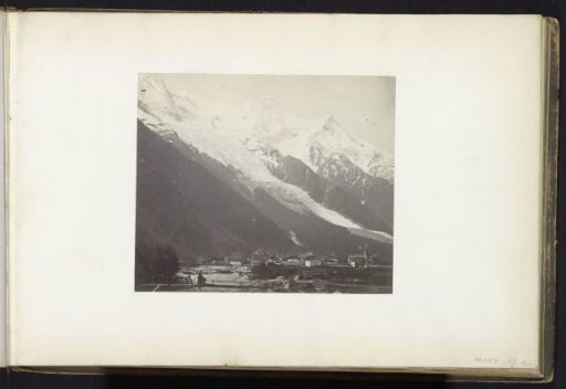 View of a village at the foot of mountains and a glacier, probably in the Alps