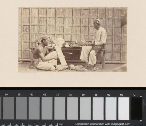 Portrait of two Indonesian men sitting at a table with pineapples