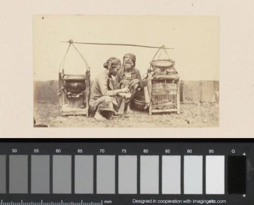 Portrait of two Indonesian women crouching by a carrying pole