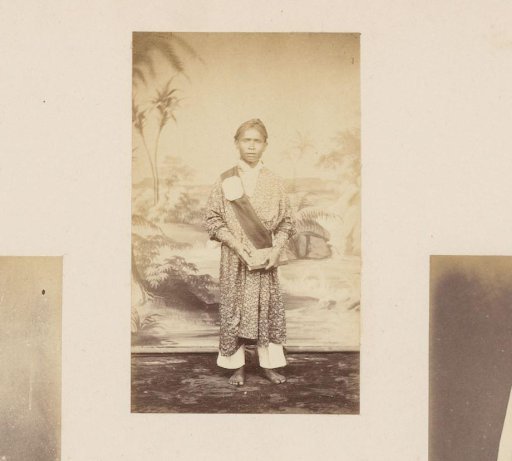 Portrait of an Indonesian man in a long robe with a sash and a book in his hand