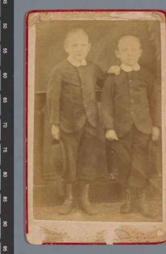 Two boys in suits holding a hat