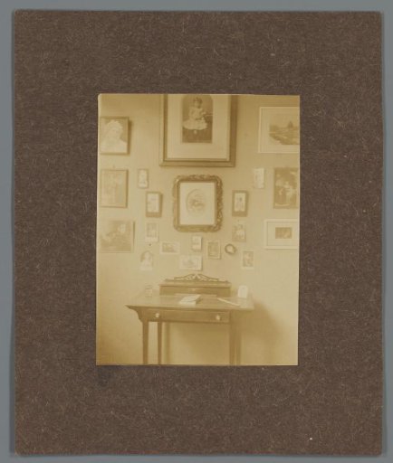 Interior with writing desk and a wall with framed portraits, possibly of the Asser family