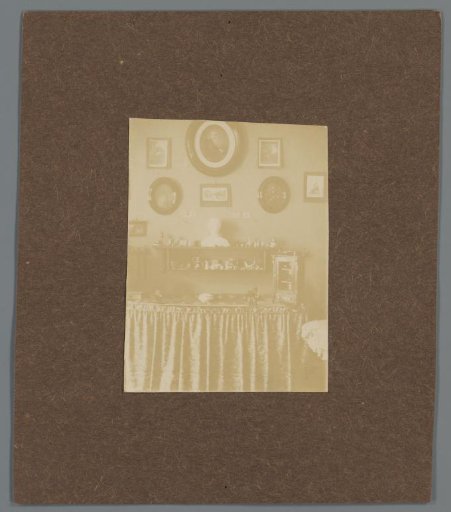 Interior with table with various decorations and a wall with portraits, possibly of the Asser family