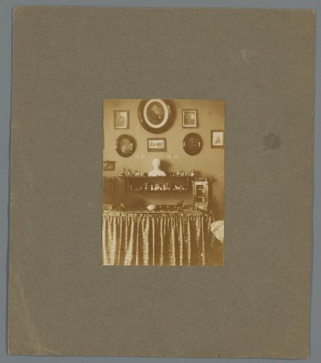 Interior with table with various decorations and a wall with portraits, possibly of the Asser family