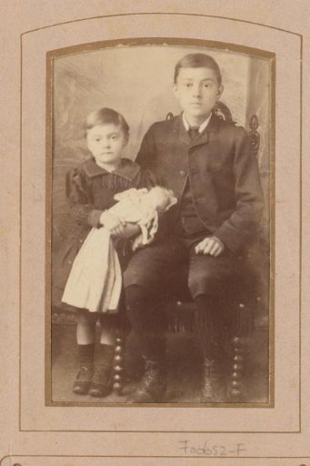 Portrait of a seated boy and a girl with a doll
