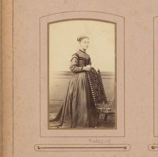 Portrait of a young woman, standing by a chair